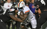 Nov 9, 2023; Louisville, Kentucky, USA; Virginia Cavaliers running back Kobe Pace (5) runs the ball against Louisville Cardinals defensive lineman Dezmond Tell (99) during the second half at L&N Federal Credit Union Stadium. Louisville defeated Virginia 31-24. Mandatory Credit: Jamie Rhodes-Imagn Images
