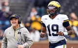 Michigan offensive coordinator Jason Beck, left, head coach Kyle Whittingham, center, and quarterback Bryce Underwood run across