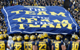 Michigan Wolverines football fans unfurl a 'The Team, The Team, The Team' banner.