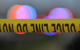 Police tape is strung up with police sirens flashing in the background - © John Oliva/Caller-Times / USA TODAY NETWORK