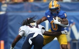 Aug 30, 2025; Pittsburgh, Pennsylvania, USA; Pittsburgh Panthers running back Desmond Reid (0) carries the ball against Duquesne Dukes defensive back Dallas Harper (12) during the first quarter at Acrisure Stadium. Mandatory Credit: Charles LeClaire-Imagn Images