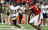 Nov 8, 2025; Louisville, Kentucky, USA; California Golden Bears wide receiver Jacob de Jesus (21) runs the ball against Louisville Cardinals defensive lineman Wesley Bailey (23) in overtime at L&N Federal Credit Union Stadium. California defeated Louisville 29-26. Mandatory Credit: Jamie Rhodes-Imagn Images