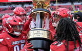 Nov 29, 2025; Louisville, Kentucky, USA; Louisville Cardinals celebrate with the Governor’s Cup after defeating the Kentucky Wildcats at L&N Federal Credit Union Stadium. Louisville defeated Kentucky 41-0. Mandatory Credit: Jamie Rhodes-Imagn Images