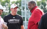 As UofL football's chief of staff Greg Brohm smiles, Vince Marrow, UofL's new executive director of player personnel and recruiting, talks during a recent Louisville football practice. Marrow left Kentucky after serving as assistant coach under head coach Mark Stoops. July 30, 2025.