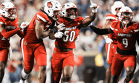Louisville Cardinals defensive lineman Clev Lubin (50) and teammates Louisville Cardinals defensive back Tayon Holloway (25), left, and Louisville Cardinals defensive lineman Wesley Bailey (23) and Louisville Cardinals linebacker Antonio Watts (9) celebrate creating a turnover on James Madison University as the Cards' beat the visiting Dukes 28-14 Friday September 5, 2025 at L&N Credit Union Stadium in Louisville, Kentucky.