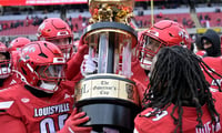 Nov 29, 2025; Louisville, Kentucky, USA; Louisville Cardinals celebrate with the Governor’s Cup after defeating the Kentucky Wildcats at L&N Federal Credit Union Stadium. Louisville defeated Kentucky 41-0. Mandatory Credit: Jamie Rhodes-Imagn Images