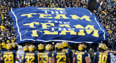 Michigan Wolverines football fans unfurl a 'The Team, The Team, The Team' banner.