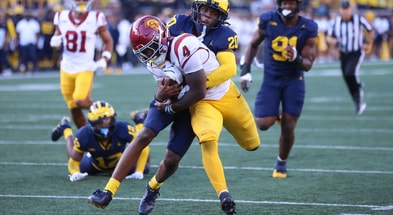 USC running back Woody Marks holds onto the ball while being tackled in a game against the Michigan Wolverines