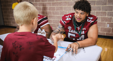 South Carolina offensive lineman Kam Pringle signing an autograph for a young fan. Photo by: Katie Dugan | GamecockCentral