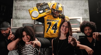 Braylon Ellison points to the camera with his family, including his father, Atiyyah Ellison, and brother, Tyson Ellison (Photo by Mizzou Football)