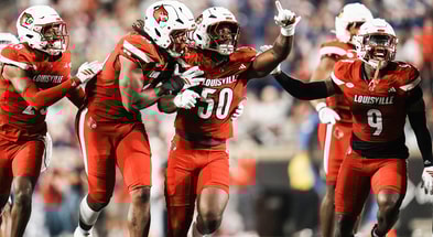 Louisville Cardinals defensive lineman Clev Lubin (50) and teammates Louisville Cardinals defensive back Tayon Holloway (25), left, and Louisville Cardinals defensive lineman Wesley Bailey (23) and Louisville Cardinals linebacker Antonio Watts (9) celebrate creating a turnover on James Madison University as the Cards' beat the visiting Dukes 28-14 Friday September 5, 2025 at L&N Credit Union Stadium in Louisville, Kentucky.