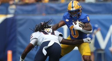 Aug 30, 2025; Pittsburgh, Pennsylvania, USA; Pittsburgh Panthers running back Desmond Reid (0) carries the ball against Duquesne Dukes defensive back Dallas Harper (12) during the first quarter at Acrisure Stadium. Mandatory Credit: Charles LeClaire-Imagn Images