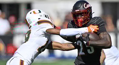 Oct 19, 2024; Louisville, Kentucky, USA; Louisville Cardinals running back Isaac Brown (25) runs the ball against Miami Hurricanes defensive back D'Yoni Hill (19) during the first half at L&N Federal Credit Union Stadium. Mandatory Credit: Jamie Rhodes-Imagn Images