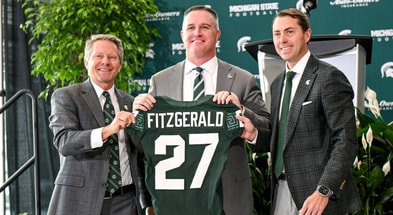 Michigan State football's new coach Pat Fitzgerald, center, holds up a jersey with MSU president KevinGuskiewicz, left, and athletic director J Batt, right, during Fitzgerald's introductory press conference. - Nick King, USA TODAY Sports
