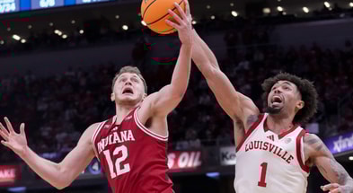 Indiana Hoosiers forward Tucker DeVries (12) and Louisville Cardinals guard J'Vonne Hadley (1) battle for control of the ball during a game Saturday, Dec. 6, 2025, at Gainbridge Fieldhouse in Indianapolis. Louisville defeated Indiana 87-78.