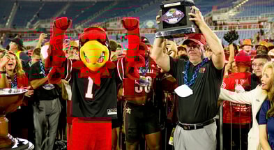 Dec 23, 2025; Boca Raton, FL, USA; Louisville Cardinals head coach Jeff Brohm raises the trophy after defeating the Toledo Rockets in the Boca Raton Bowl at Flagler CU Stadium. Mandatory Credit: Jeff Romance-Imagn Images