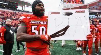 Louisville Cardinals defensive lineman Clev Lubin (50) held a coach's whiteboard with the letters BTA and carried a belt after the Cards dominated rival Kentucky 41-0 Saturday, November 29, 2025 in Louisville, Kentucky.