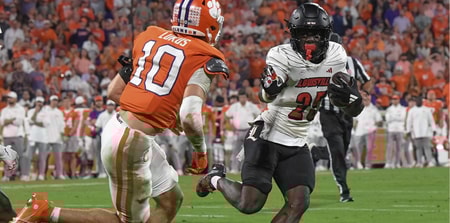 Nov 2, 2024; Clemson, South Carolina, USA; Louisville Cardinals running back Isaac Brown (25) runs the ball against Clemson Tigers cornerback Jeadyn Lukus (10) during the second quarter at Memorial Stadium. Mandatory Credit: Ken Ruinard-Imagn Images