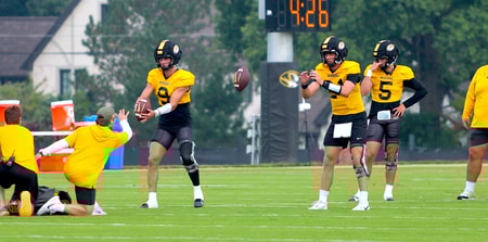 Beau Pribula (9) and Sam Horn (21) catch snaps during a drill while Matt Zollers (5) looks on