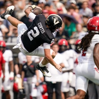 Vanderbilt quarterback Jared Curtis (2) leaps over NC State defensive back Ty White (10) during the second quarter at FirstBank