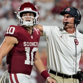 Oklahoma Sooners quarterback John Mateer (10) and coach Brent Venables talk after a play during a college football game between
