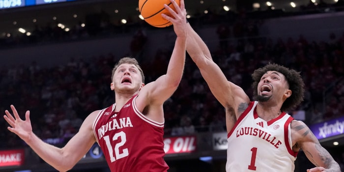 Indiana Hoosiers forward Tucker DeVries (12) and Louisville Cardinals guard J'Vonne Hadley (1) battle for control of the ball during a game Saturday, Dec. 6, 2025, at Gainbridge Fieldhouse in Indianapolis. Louisville defeated Indiana 87-78.