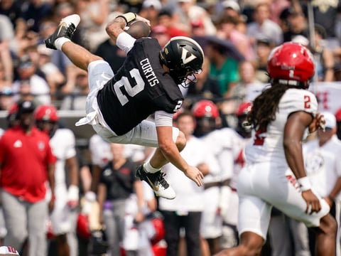 Vanderbilt quarterback Jared Curtis (2) leaps over NC State defensive back Ty White (10) during the second quarter at FirstBank