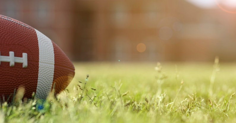 American football on stadium field at school campus.