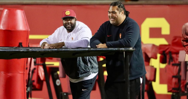 USC defensive line coach Eric Henderson and Shaun Nua watch the Trojans warm up before a spring ball practice