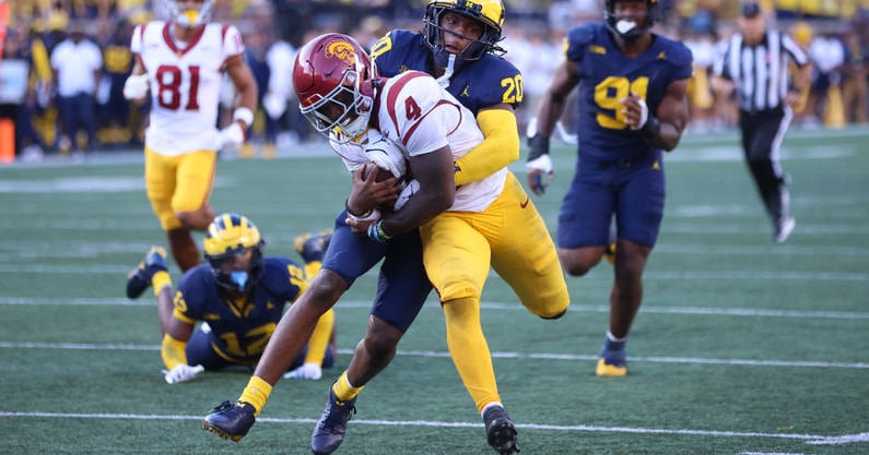 USC running back Woody Marks holds onto the ball while being tackled in a game against the Michigan Wolverines