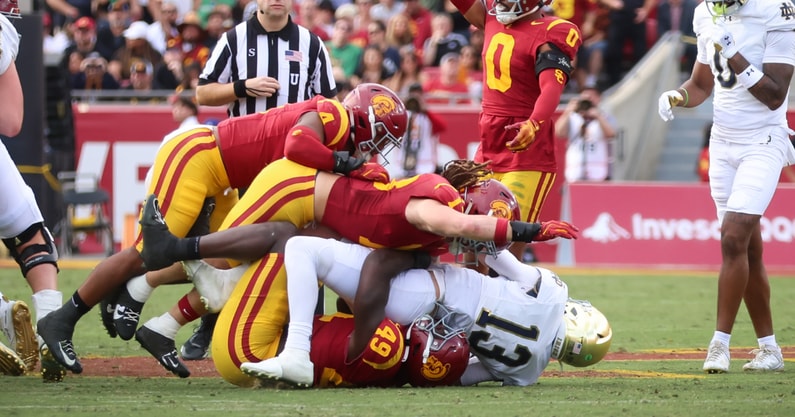 USC defenders finish off a tackle of Notre Dame quarterback Riley Leonard during a game between the Trojans and Fighting Irish