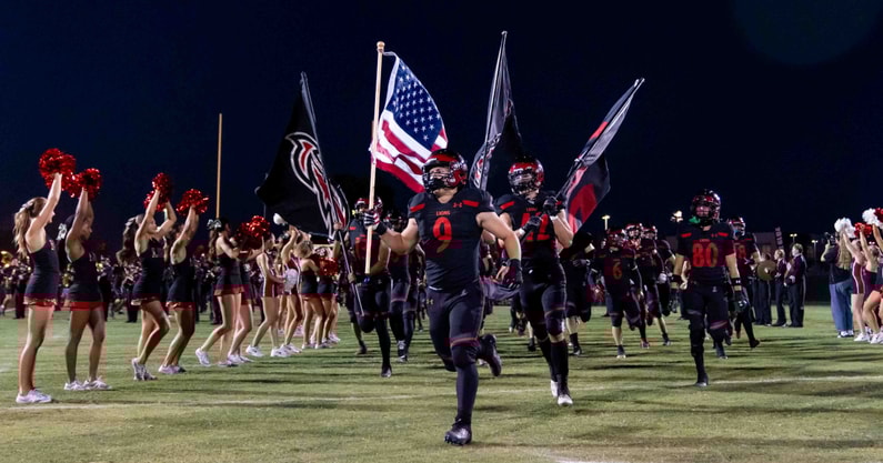Liberty Lions run onto the field prior to an Arizona high school football game against the Centennial Huskies.