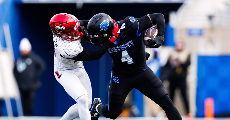 Nov 30, 2024; Lexington, Kentucky, USA; Kentucky Wildcats running back Chip Trayanum (4) is tackled by Louisville Cardinals defensive back Tahveon Nicholson (23) during the fourth quarter at Kroger Field. Mandatory Credit: Jordan Prather-Imagn Images