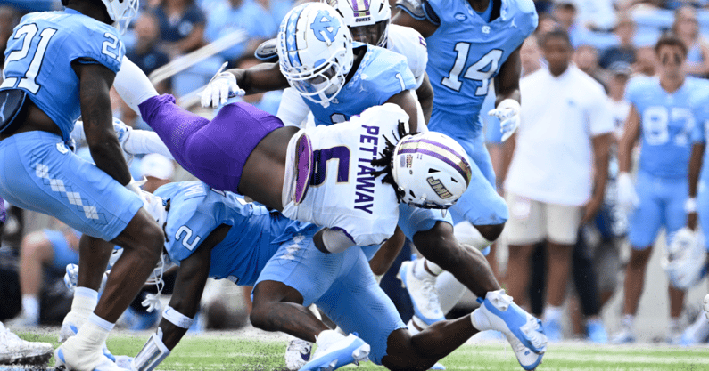 Sep 21, 2024; Chapel Hill, North Carolina, USA; James Madison Dukes running back George Pettaway (6) is tackled by North Carolina Tar Heels defensive backs Kaleb Cost (21) and Jakeen Harris (2) and Antavious Lane (1) in the second quarter at Kenan Memorial Stadium. Mandatory Credit: Bob Donnan-Imagn Images