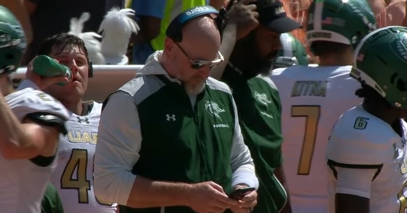 UAB coach Trent Dilfer on his phone before Saturday's game at Tennessee.