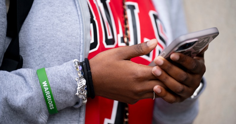 A Tennessee student uses a cell phone before putting it in a Yondr pouch during the school day, via Denny Simmons : The Tennessean : USA TODAY NETWORK via Imagn Images