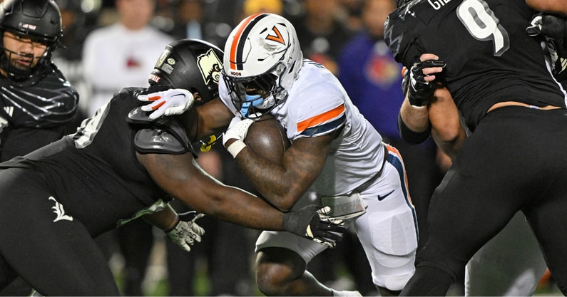 Nov 9, 2023; Louisville, Kentucky, USA; Virginia Cavaliers running back Kobe Pace (5) runs the ball against Louisville Cardinals defensive lineman Dezmond Tell (99) during the second half at L&N Federal Credit Union Stadium. Louisville defeated Virginia 31-24. Mandatory Credit: Jamie Rhodes-Imagn Images