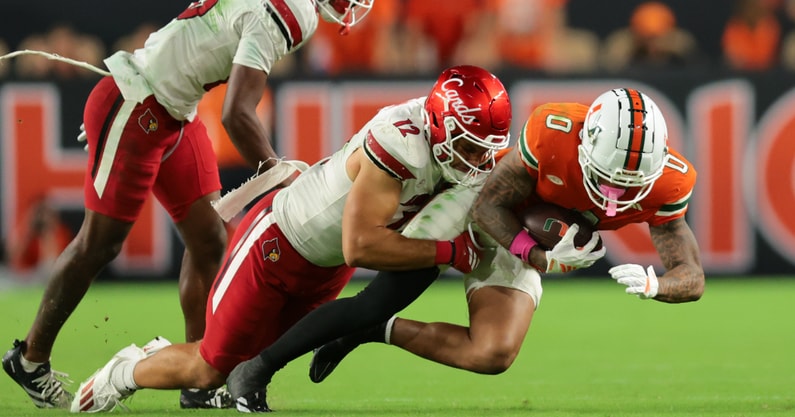 Oct 17, 2025; Miami Gardens, Florida, USA; Miami Hurricanes wide receiver Keelan Marion (0) carries the football against Louisville Cardinals linebacker Kalib Perry (12) during the third quarter at Hard Rock Stadium. Mandatory Credit: Sam Navarro-Imagn Images