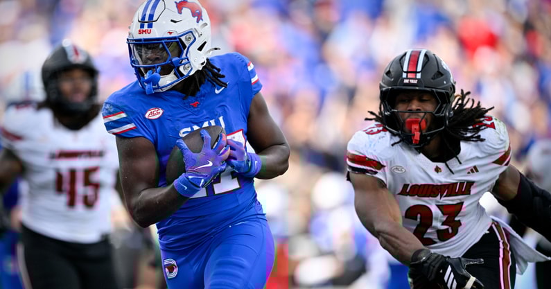 Nov 22, 2025; Dallas, Texas, USA; SMU Mustangs running back T.J. Harden (27) eludes the tackle of Louisville Cardinals defensive lineman Wesley Bailey (23) for a touchdown during the first half at Gerald J. Ford Stadium. Mandatory Credit: Jerome Miron-Imagn Images