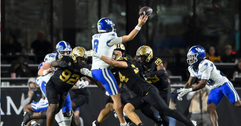 Nov 22, 2025; Nashville, Tennessee, USA; Kentucky Wildcats quarterback Cutter Boley (8) gets hit as he release the ball by Vanderbilt Commodores defensive lineman Jaylon Stone (92) and linebacker Nick Rinaldi (24) during the second half at FirstBank Stadium. Mandatory Credit: Steve Roberts-Imagn Images