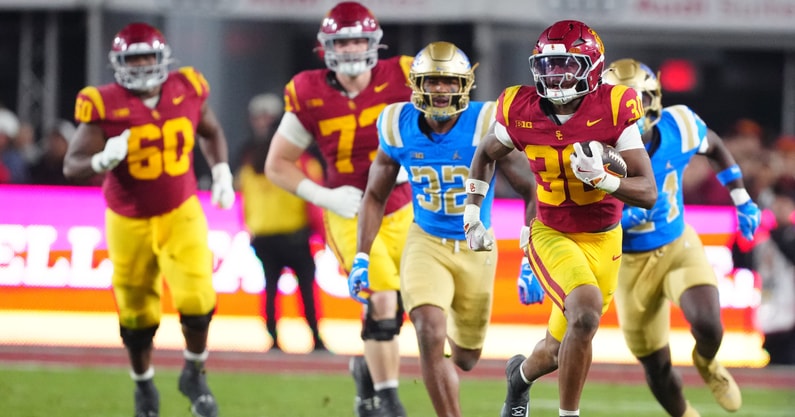 USC Trojans running back King Miller (30) carries the ball against UCLA Bruins linebacker Isaiah Chisom (32) in the first half at United Airlines Field at Los Angeles Memorial Coliseum