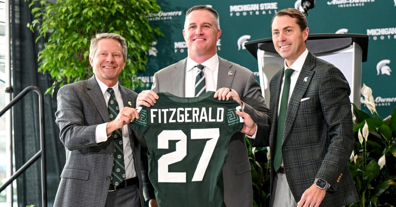 Michigan State football's new coach Pat Fitzgerald, center, holds up a jersey with MSU president KevinGuskiewicz, left, and athletic director J Batt, right, during Fitzgerald's introductory press conference. - Nick King, USA TODAY Sports