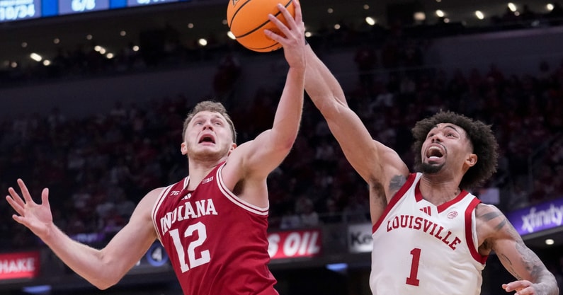 Indiana Hoosiers forward Tucker DeVries (12) and Louisville Cardinals guard J'Vonne Hadley (1) battle for control of the ball during a game Saturday, Dec. 6, 2025, at Gainbridge Fieldhouse in Indianapolis. Louisville defeated Indiana 87-78.