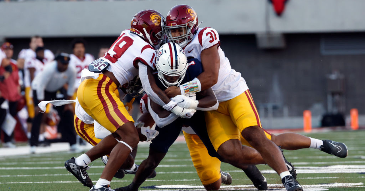 Wide receiver Anthony Simpson #1 of the Arizona Wildcats is tackled by defensive lineman Tyrone Taleni #31 and defensive back Jaylin Smith #19 of the USC Trojans during the first half of the game at Arizona Stadium on October 29, 2022 in Tucson, Arizona. 