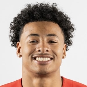 Headshot of a smiling young male athlete with curly hair, wearing a red jersey.