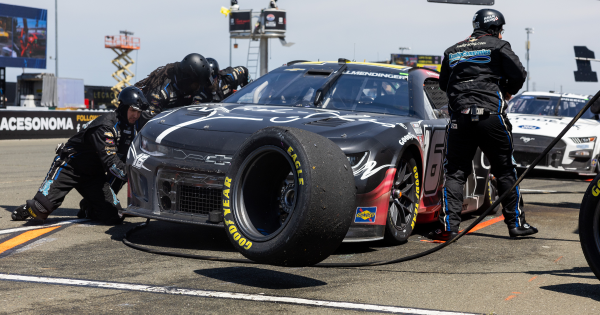 NASCAR pit crew members help fix up a car after fender bender in Chicago