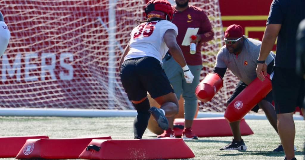 USC defensive line coach Eric Henderson works with Trojans' defensive end DJ Peevy during a drill