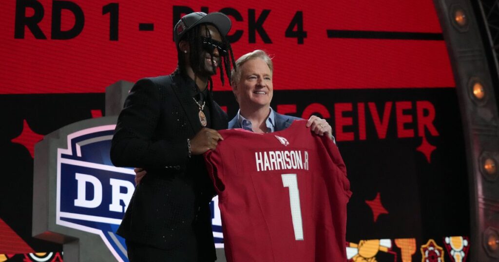 Former Ohio State wideout Marvin Harrison Jr. holds up his new Arizona Cardinals jersey with NFL Commissioner Roger Goodell. (Kirby Lee-USA TODAY Sports)