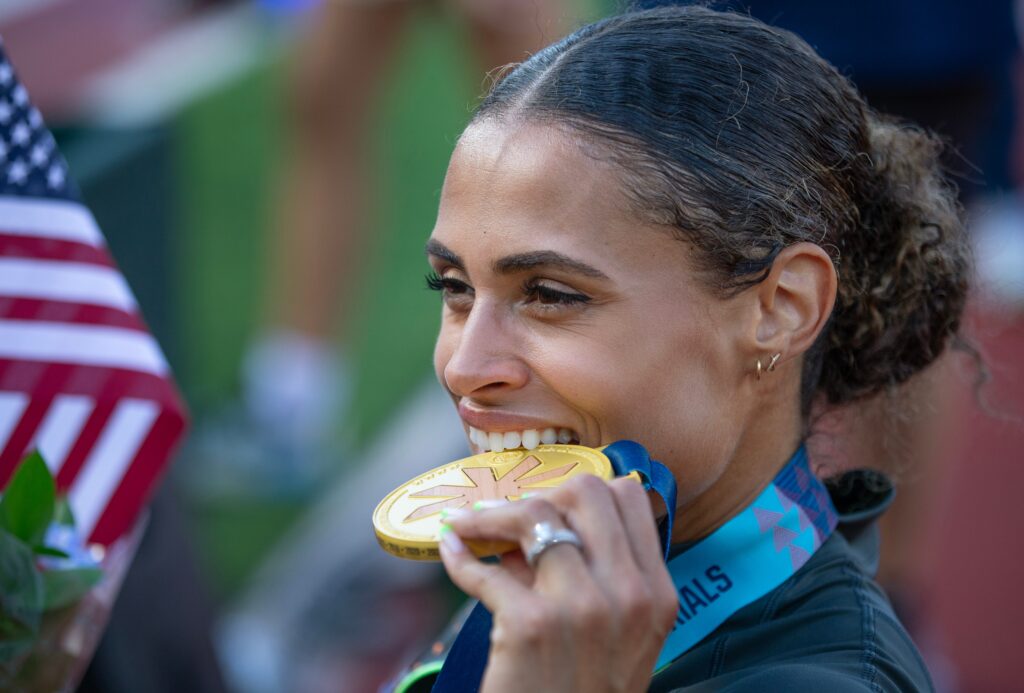 Sydney McLaughlin-Levrone takes a bite on her gold medal after breaking the world record in the women’s 400 hurdles on the final day of the U.S. Olympic Track & Field Trials in Eugene Sunday, June 30, 2024 - © Chris Pietsch/The Register-Guard / USA TODAY NETWORK