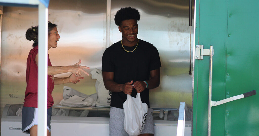 FSU wide receiver BJ Gibson carries food to a family at Tuesday's community outreach event. (Matt LaSerre/Warchant)